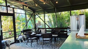 A covered outdoor seating area with wicker furniture, a patterned rug, and a view of lush greenery. - Spacious Historic Estate ~ 5 Min Walk to Hilo & Bay Front (Hilo)