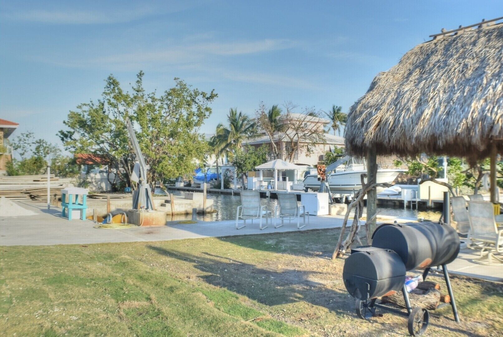 A marina with boats, a barbecue grill, and a thatched-roof structure.