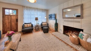 A living room with a fireplace, a sofa, a coffee table, and a rug. - Desert Gardens #1 (Moab)