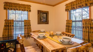 A dining area with a wooden table set for four, surrounded by chairs. There is a framed picture on the wall above the table. - Private, Super Fast WiFi Free, NFL Sunday, VideoArcade, Fishing & 2 Pools, Gated (Sevierville)