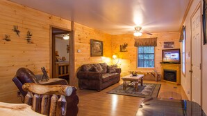 A cozy log cabin interior with a leather chair, a sofa, a dining table, and a fireplace. - Private, Super Fast WiFi Free, NFL Sunday, VideoArcade, Fishing & 2 Pools, Gated (Sevierville)