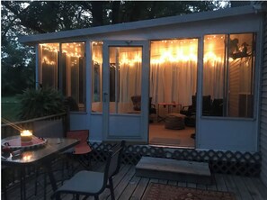 Un espace extérieur abrité, aménagé avec une table et des chaises, un banc et un petit tapis.