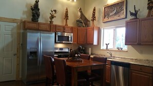 A modern kitchen with wooden cabinets, stainless steel appliances, and decorative animal figurines. - Walk to The RIVER! Brand New 3 Bed/2 Bath. W/ FIRE PIT! (Sterling)