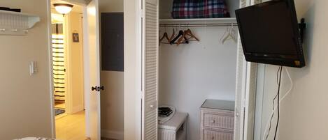 A bedroom with a bed, a television mounted on the wall, a wardrobe, and a small table.