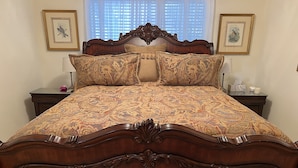 A bed with a floral patterned bedspread, wooden headboard, and two nightstands with lamps and a tissue box.