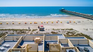A beach with a pier, sun loungers, and umbrellas. - Oceanfront with Endless Ocean Views (Folly Beach)