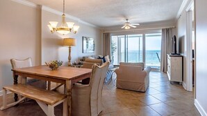 Un vaste espace de vie comprenant une table à manger en bois, des chaises de couleur beige, un canapé et un téléviseur.