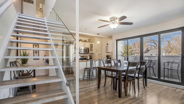 Una cocina moderna con comedor, una escalera y un amplio ventanal corredera al exterior.