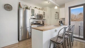 Una cocina moderna con electrodomésticos de acero inoxidable, una isla de madera y taburetes de bar.