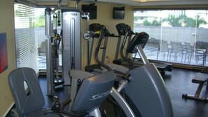 Un gimnasio con varios equipos de ejercicio, incluyendo una máquina elíptica Cybex y una cinta de correr.