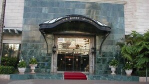 La entrada al hotel The Royal Garden, con fachada de mármol y una alfombra roja que conduce a la entrada.