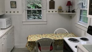 Una cocina funcional con una mesa de comedor, sillas, microondas y estufa.