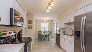 Eine moderne Küche mit Einbauofen, Edelstahlkühlschrank und einer Essecke mit Tisch und Stühlen.