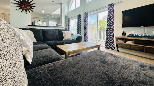 A modern living room with a dark grey sofa, a wooden coffee table, and a flat-screen TV on a wooden stand.