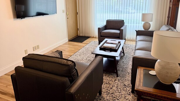 Una sala de estar moderna con televisor de pantalla plana, un sofá, una silla y una mesa de centro.