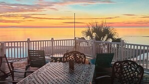 A deck with outdoor seating and a view of the sunset over the water. - Beachfront, kid friendly seas, seclusion, nature (Carrabelle)