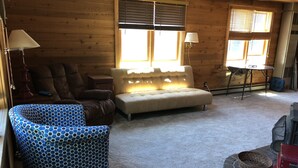 L’intérieur d’un chalet confortable, avec un canapé, un fauteuil et une petite table.
