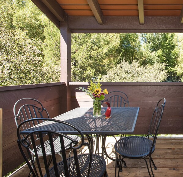 Relax on the patio surrounded by lush greenery, with a comfortable table and chairs.