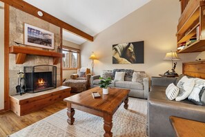 Cozy living room with a fireplace, comfortable seating, and a bookshelf.