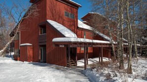 A red wooden building with a covered porch and snow on the roof. - RMR: Thistle 921 Condo in The Aspens/Wilson,WY (Wilson)