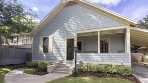A single-story house with a gabled roof, a front porch with a bench, and a small front yard with a pathway leading to the entrance. - HISTORIC DISTRICT ~ Free Parking! (Saint Augustine)