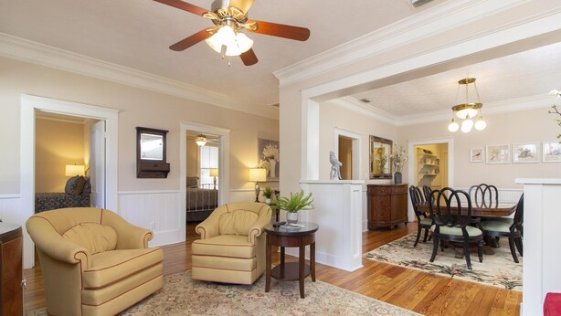 A living room with a beige armchair, a small side table with a plant, and a dining area with a wooden table and chairs. - HISTORIC DISTRICT ~ Free Parking! (Saint Augustine)