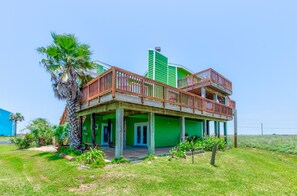 Una casa de dos pisos con un balcón de madera y fachada verde.