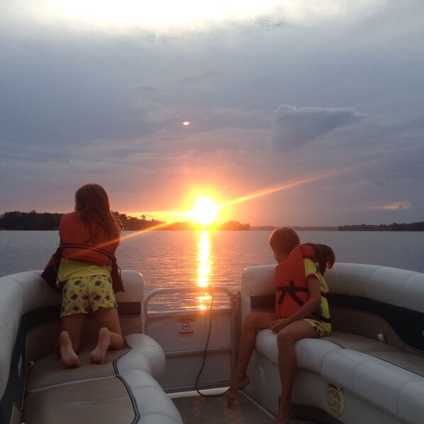 Dos personas en un bote con un atardecer de fondo.