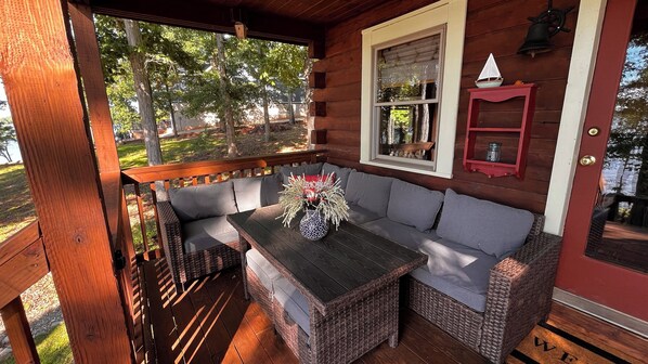 A wooden porch with a built-in seating area, a window with a view of the outdoors, and a small shelf with decorative items.