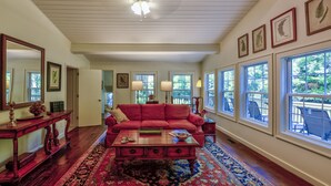 A spacious living room with a red sofa, wooden coffee table, and a large window with a view of the outdoors. - Location, Location, Location. (Highlands)
