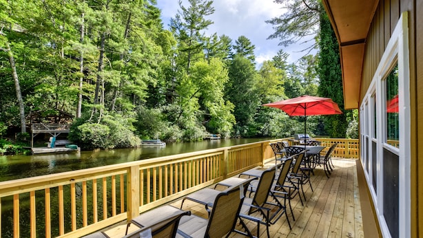 A wooden deck with outdoor seating and a view of a river surrounded by trees. - Location, Location, Location. (Highlands)