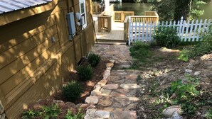 A stone pathway leading to a wooden house with a white picket fence. - Location, Location, Location. (Highlands)