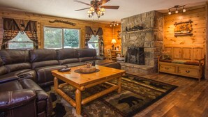 A cozy living room with a stone fireplace, leather sofa, and a wooden coffee table.