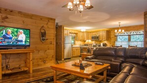 A cozy living room with a leather sofa, wooden coffee table, and a television displaying a sports event.
