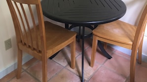 A corner table with two wooden chairs, a black metal table, and a tiled floor.