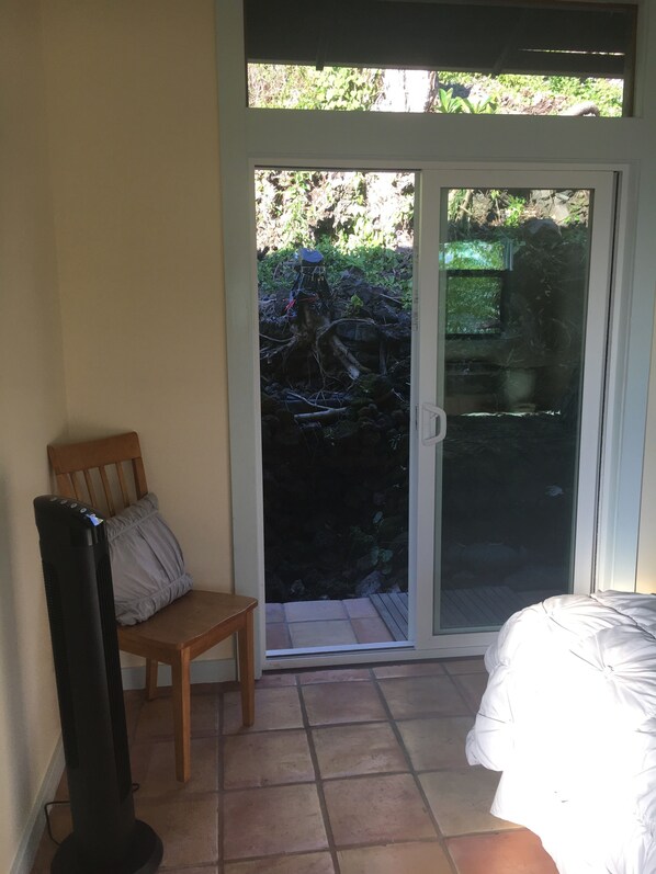 A room with a sliding glass door leading to a patio, a wooden chair, and a bed.