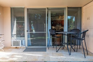 A patio area with a table and chairs, a sliding glass door, and a small air conditioning unit.