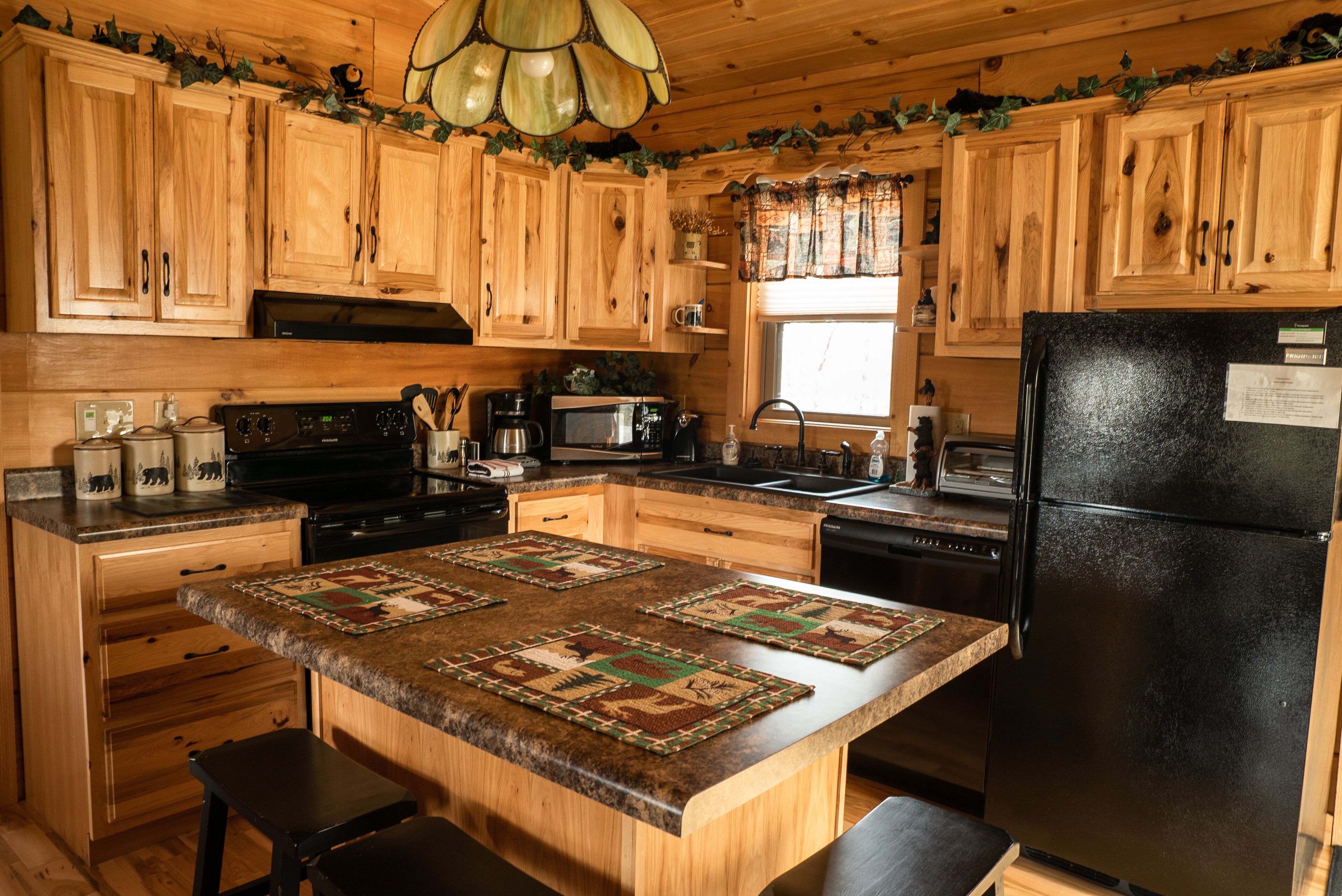 Una cocina con armarios de madera, un refrigerador negro y una isla central con un camino tejido.