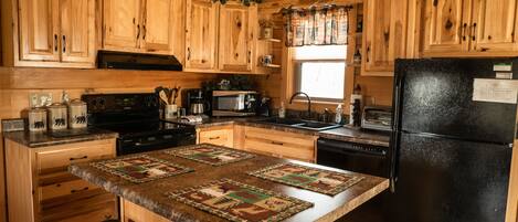Una cocina con armarios de madera, un refrigerador negro y una isla central con un camino tejido.