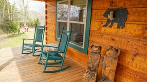 A wooden cabin with a porch, rocking chairs, and wooden bear sculptures. - Honeymoon/couples Retreat -  Private Custom Built Log Cabin - Wi-fi (Sevierville)