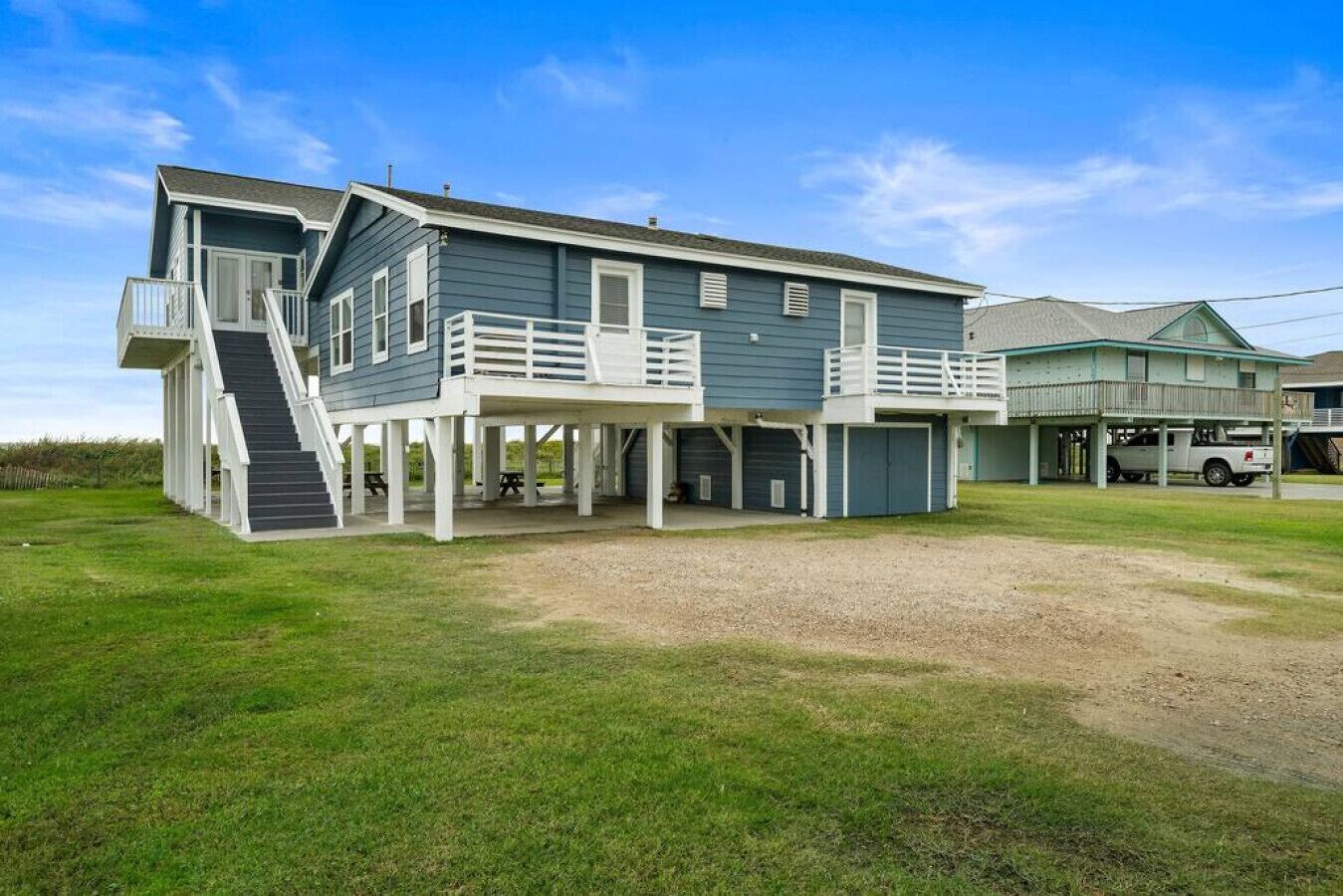 A two-story house with a covered porch and a staircase leading to a deck.