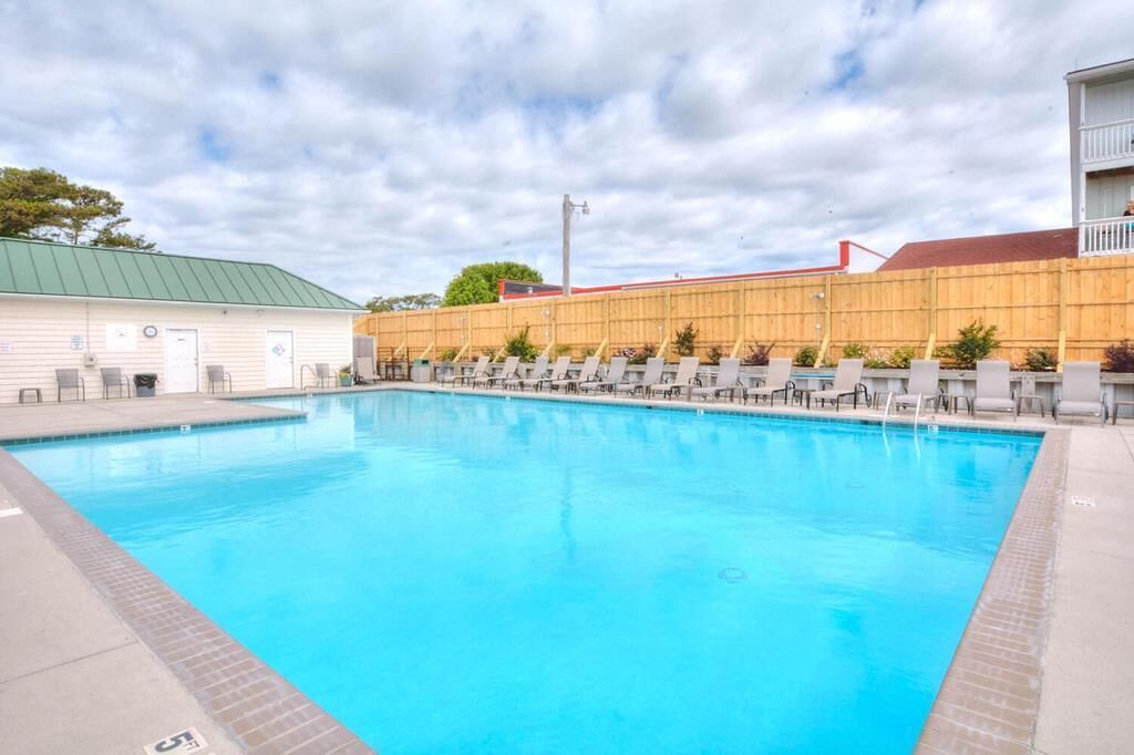 Une piscine avec des chaises longues et, au fond, un bâtiment doté d’un toit végétalisé.