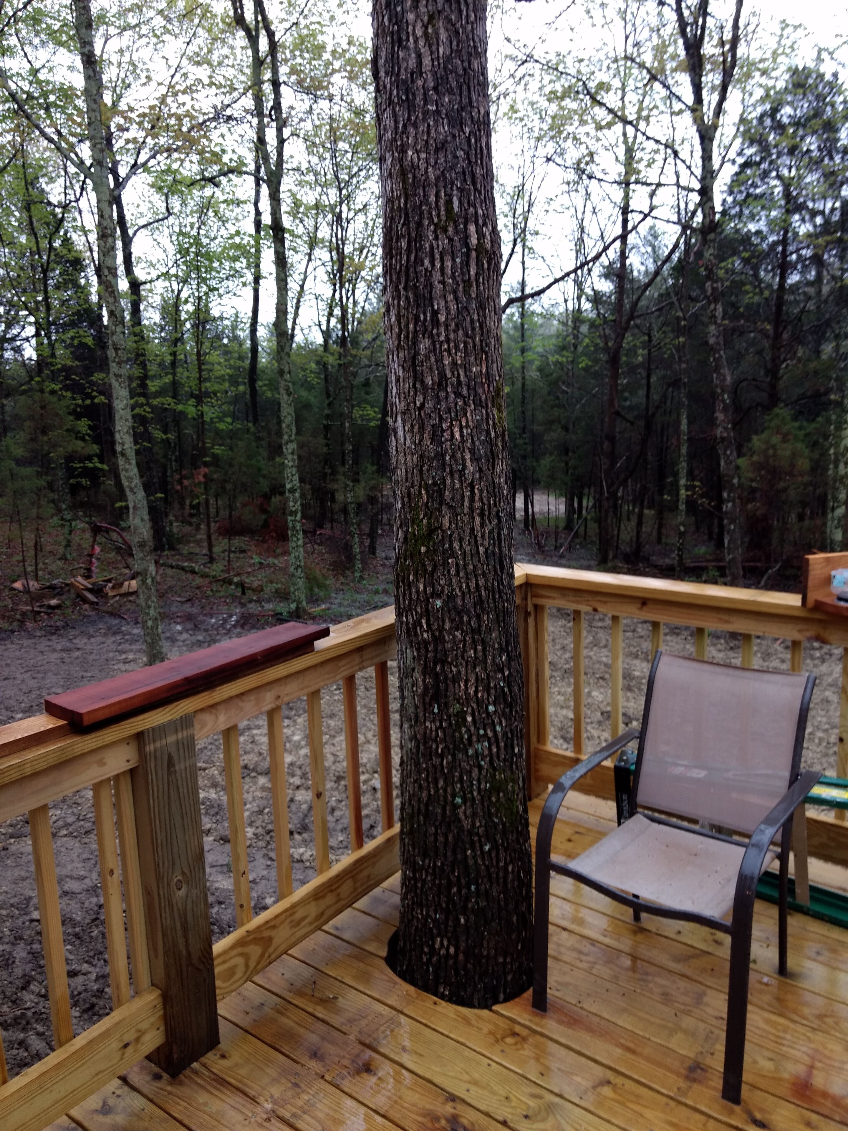 A wooden deck with a metal chair and a bench.