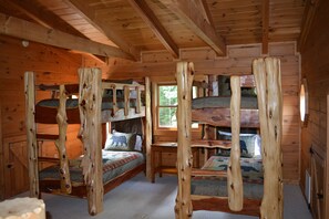 Une cabine avec trois lits superposés, des murs en bois et une fenêtre.