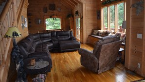A log cabin interior with a sectional sofa, a round coffee table, and a fireplace. - SPACIOUS FAMILY RETREAT NEAR ALL THE FUN! STUNNING VIEW, EASY ACCESS. (Sevierville)