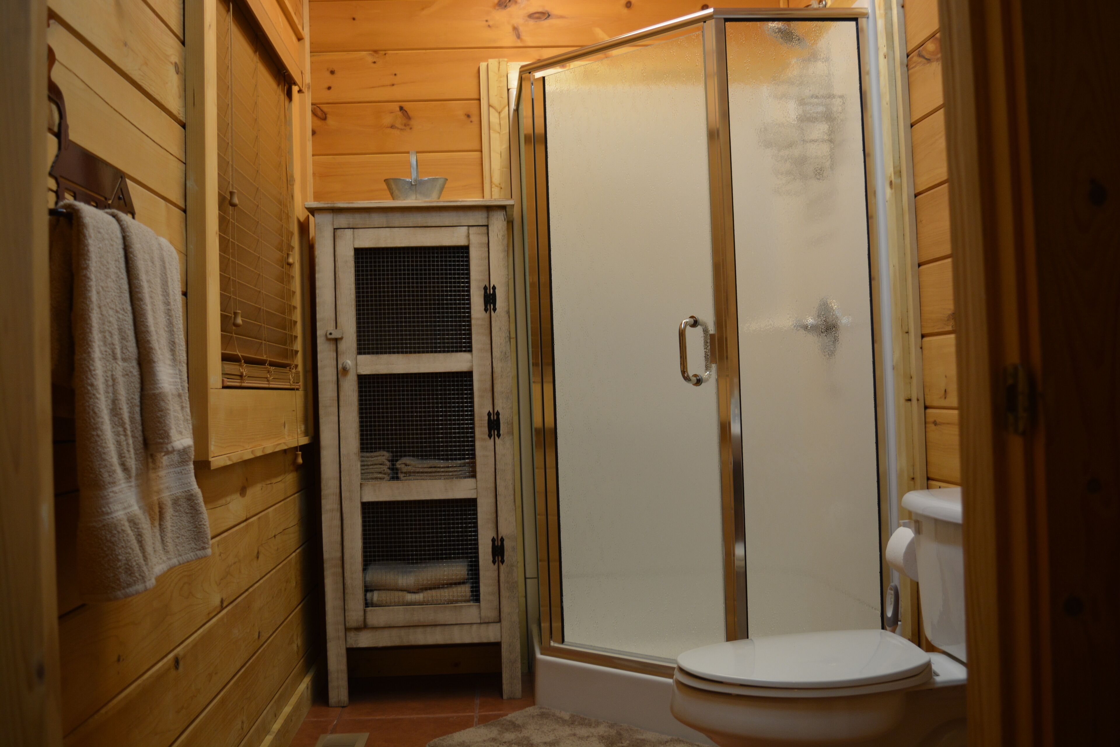 Un baño pequeño con cabina de ducha, inodoro y un mueble bajo con toallas.