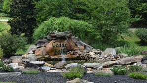 A garden with a rock formation labeled "Cedar Falls," surrounded by various plants and a small water feature. - SPACIOUS FAMILY RETREAT NEAR ALL THE FUN! STUNNING VIEW, EASY ACCESS. (Sevierville)