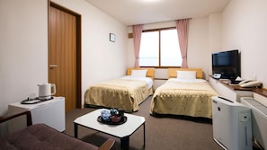 Habitación de hotel con dos camas, televisión, cafetera, teléfono y radiador.