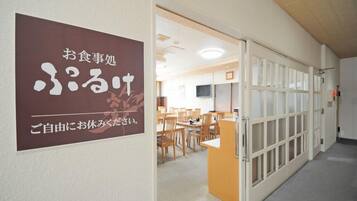 A hallway with a sign indicating a dining area, wooden chairs, and a counter.