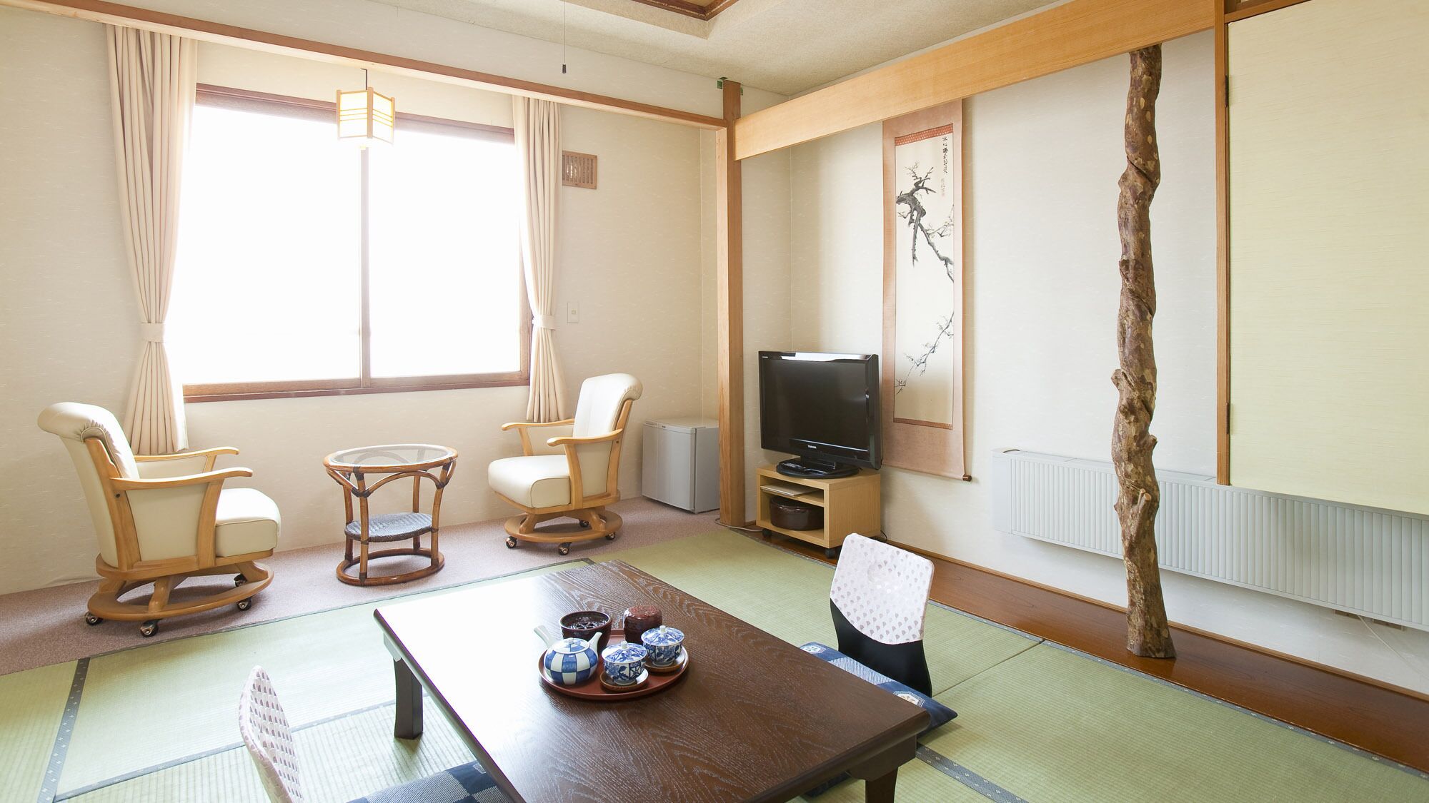 Perinteinen japanilaistyylinen huone, jossa on tatamimatto, televisio ja koristeellinen puinen puunrunko.